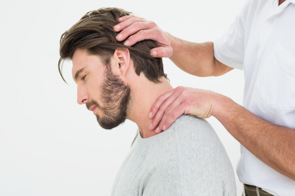 Side view of a young man getting the neck adjustment done in the medical office